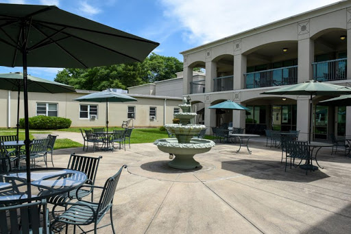A serene outdoor courtyard featuring a decorative fountain and seating areas under green umbrellas.