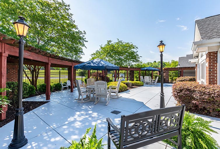 A sunny outdoor patio area with seating, umbrellas, and lush greenery.
