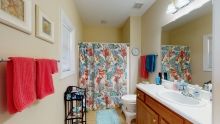 A colorful bathroom with a floral shower curtain and neatly arranged towels.