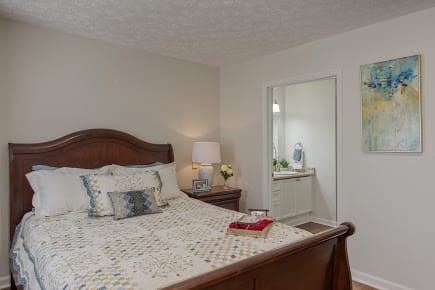 A cozy bedroom with a wooden bed, lamp, and decorative items.