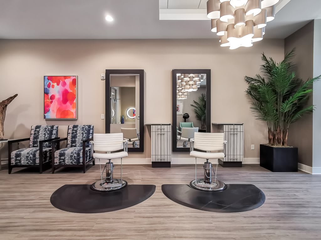 A modern salon interior featuring sleek chairs, large mirrors, and vibrant artwork.
