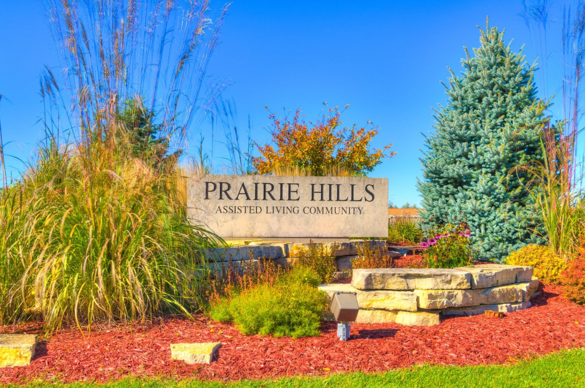 Entrance to Prairie Hills community surrounded by landscaped greenery and autumn foliage.