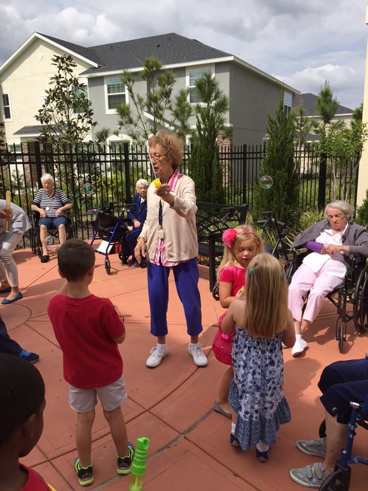 An outdoor gathering where children and elderly individuals are interacting in a community setting.