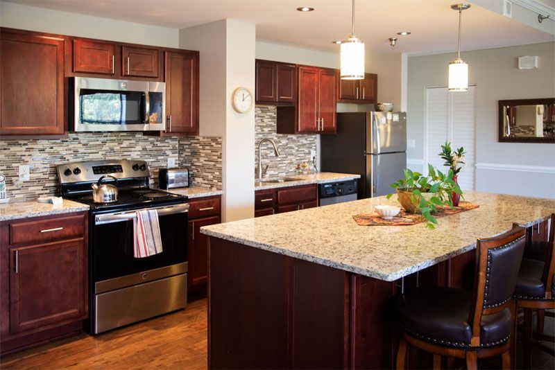 A modern kitchen featuring dark wood cabinets, stainless steel appliances, and a granite-topped island.