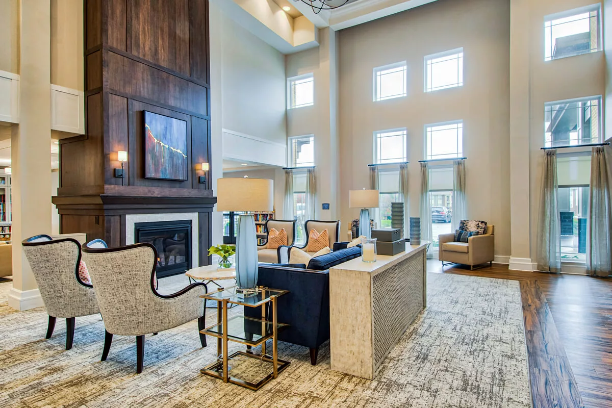 A modern living room with high ceilings, featuring elegant furniture and bright natural lighting.