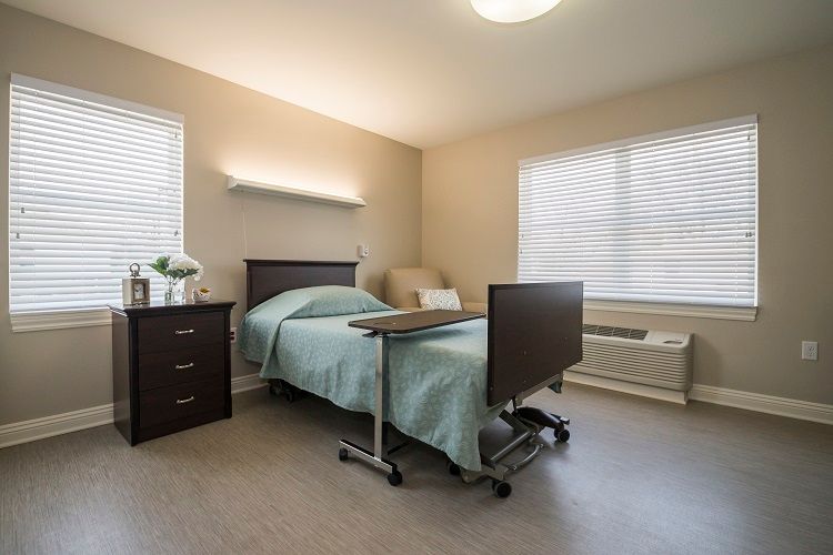 A clean and well-lit hospital room with a single bed and bedside furniture.