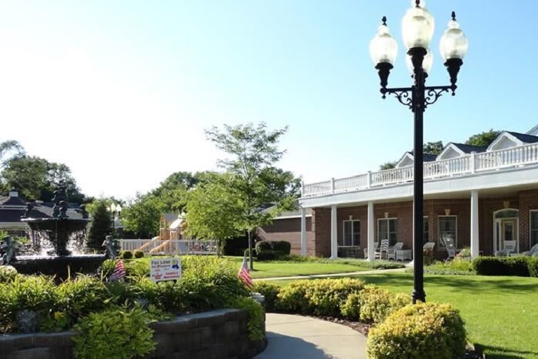 A sunny outdoor garden with a building, lamp post, and well-maintained landscaping.
