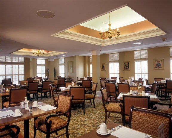 Elegant restaurant dining area with neatly arranged tables and chairs, illuminated by chandeliers.