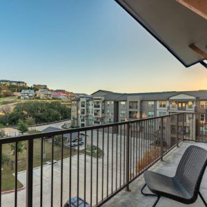 A peaceful view from a balcony overlooking an apartment complex at sunset.