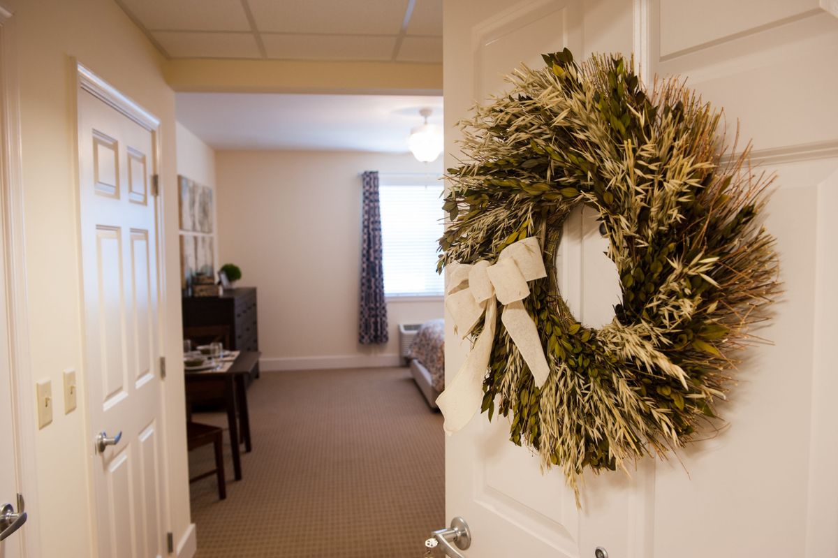 A festive wreath hangs on the door, welcoming you into a cozy and well-lit room.