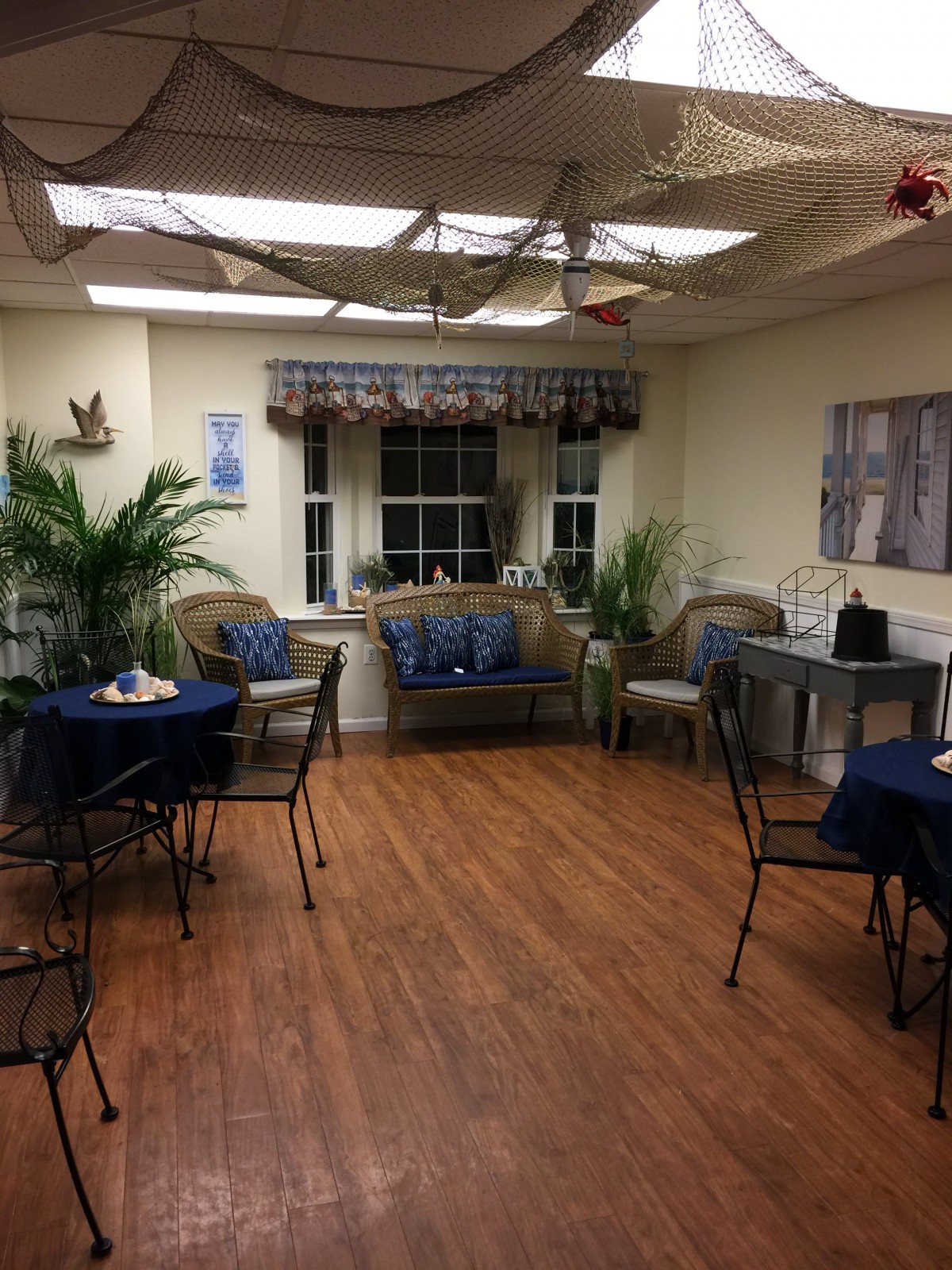 A cozy indoor seating area with tables, chairs, and a couch surrounded by plants.