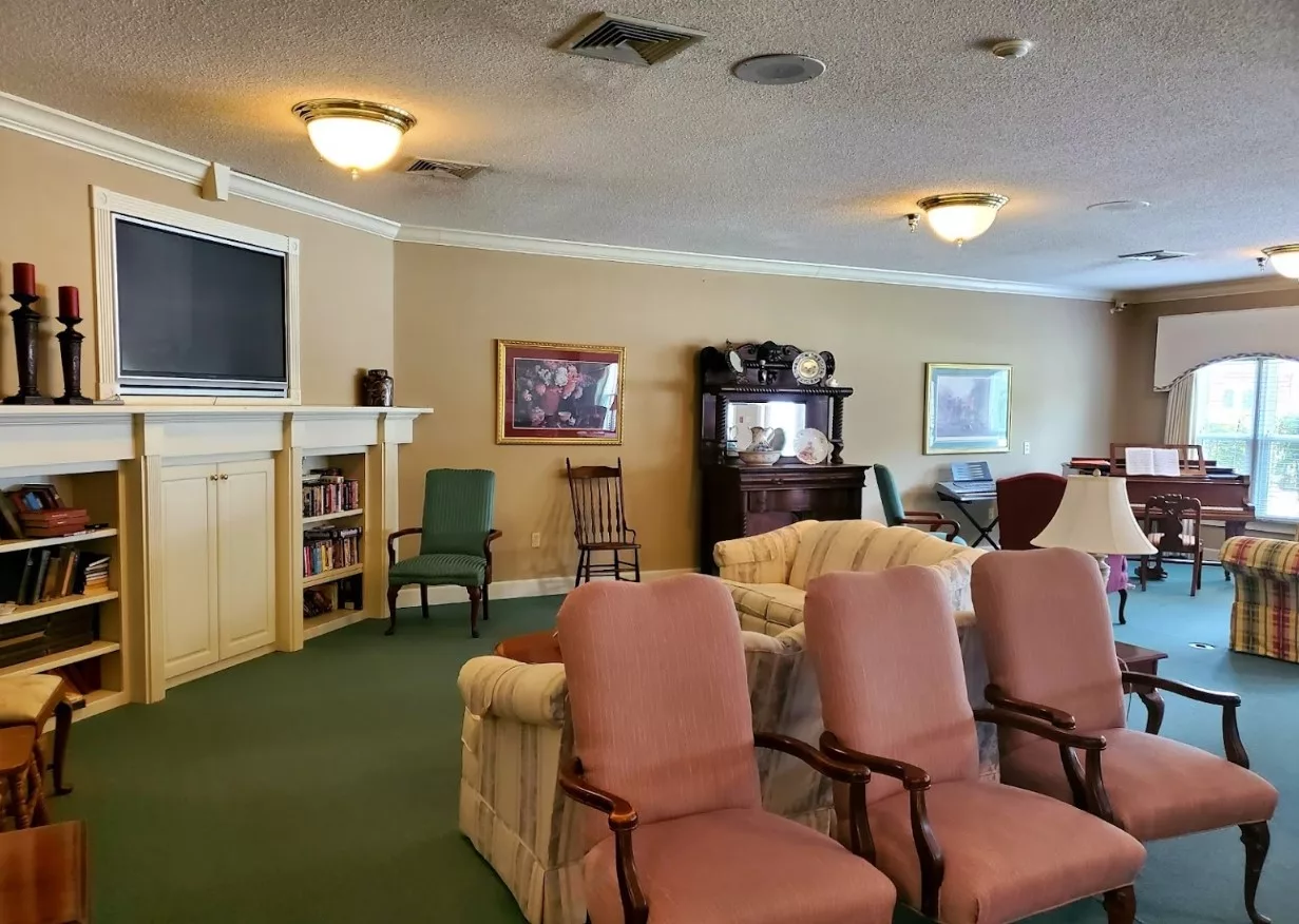 A cozy living room with various seating options, a bookshelf, and decorative paintings.
