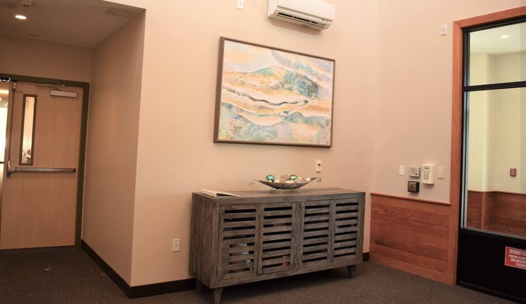 A cozy interior with a sideboard, abstract artwork, and an air conditioner on the wall.