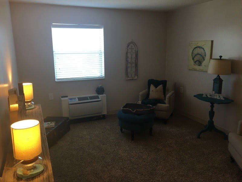A cozy living room with a single chair, small table, and wall decor.