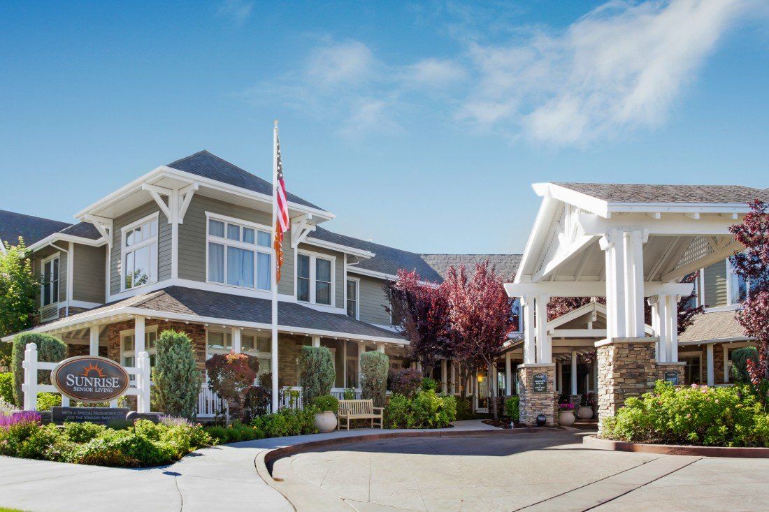 A well-maintained residential building with a manicured garden and an American flag flying in the front.