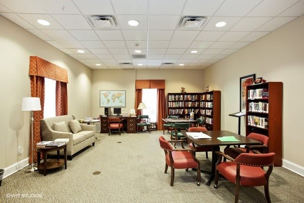 A well-furnished office space with a desk, bookshelves, and seating area.