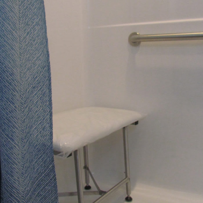 A bathroom shower area with a foldable shower chair and grab bar.