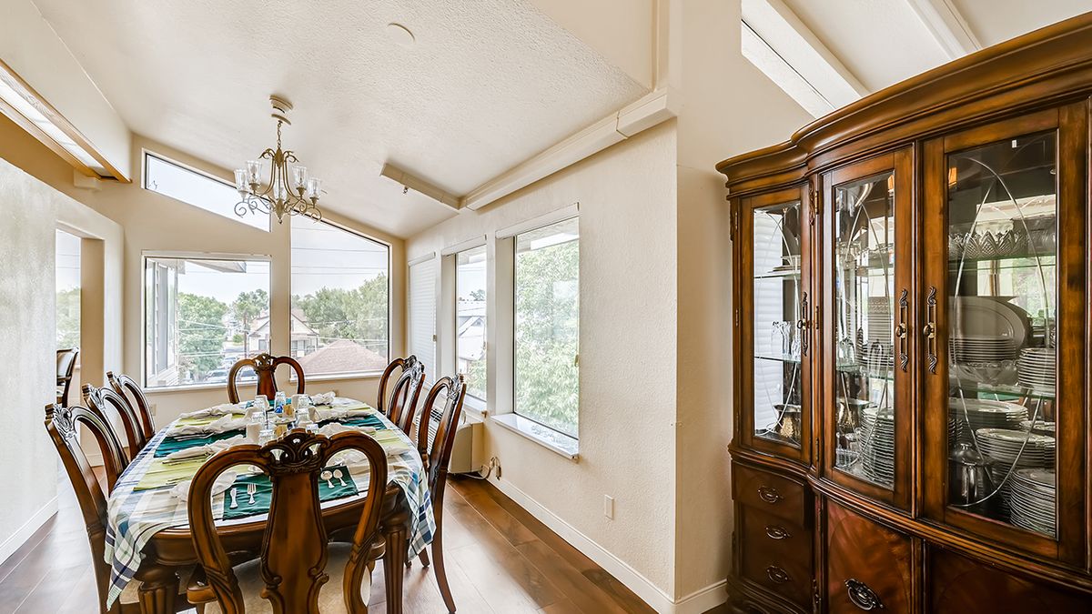 A well-lit dining room with elegant wooden furniture and large windows.