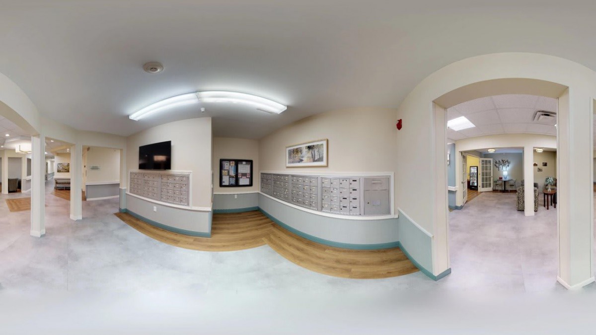 A well-lit hallway in an apartment building with rows of mailboxes on the walls.