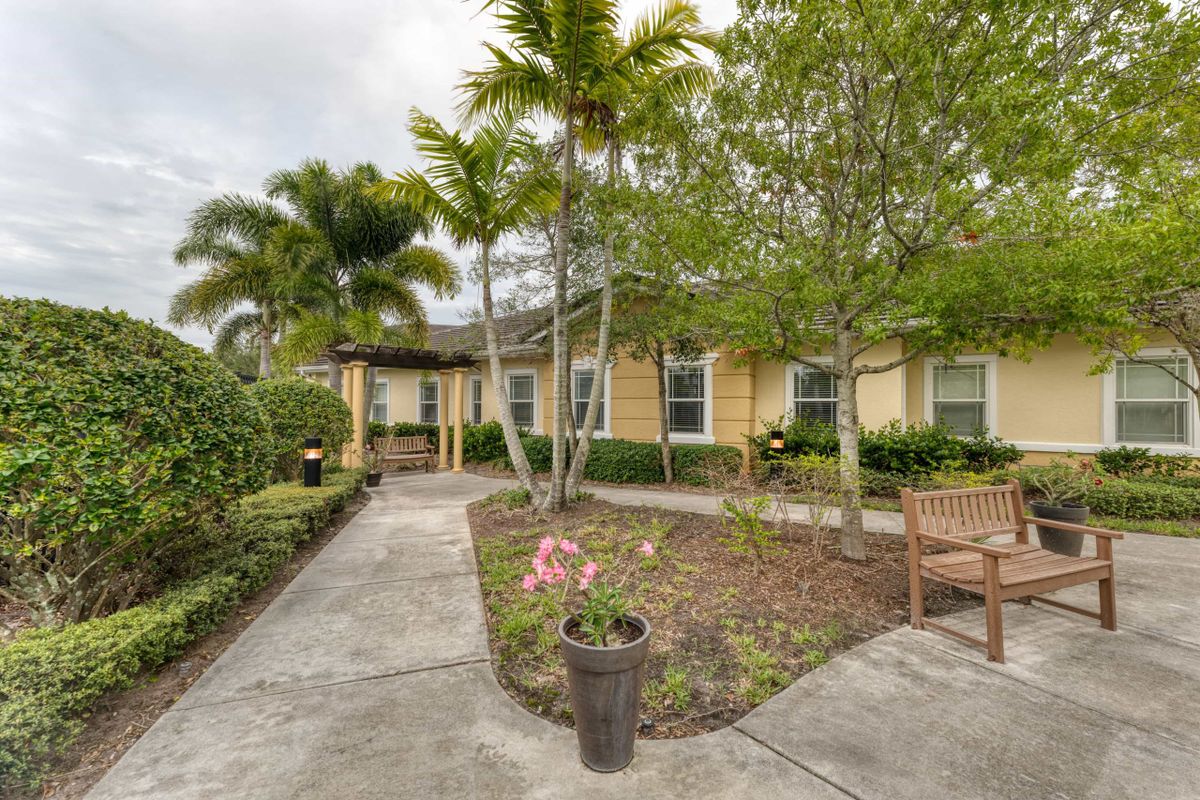 A charming residential house surrounded by lush landscaping and palm trees.