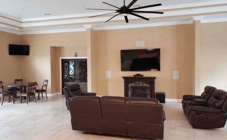 A cozy living room featuring a large sofa, wall-mounted television, and elegant fireplace.