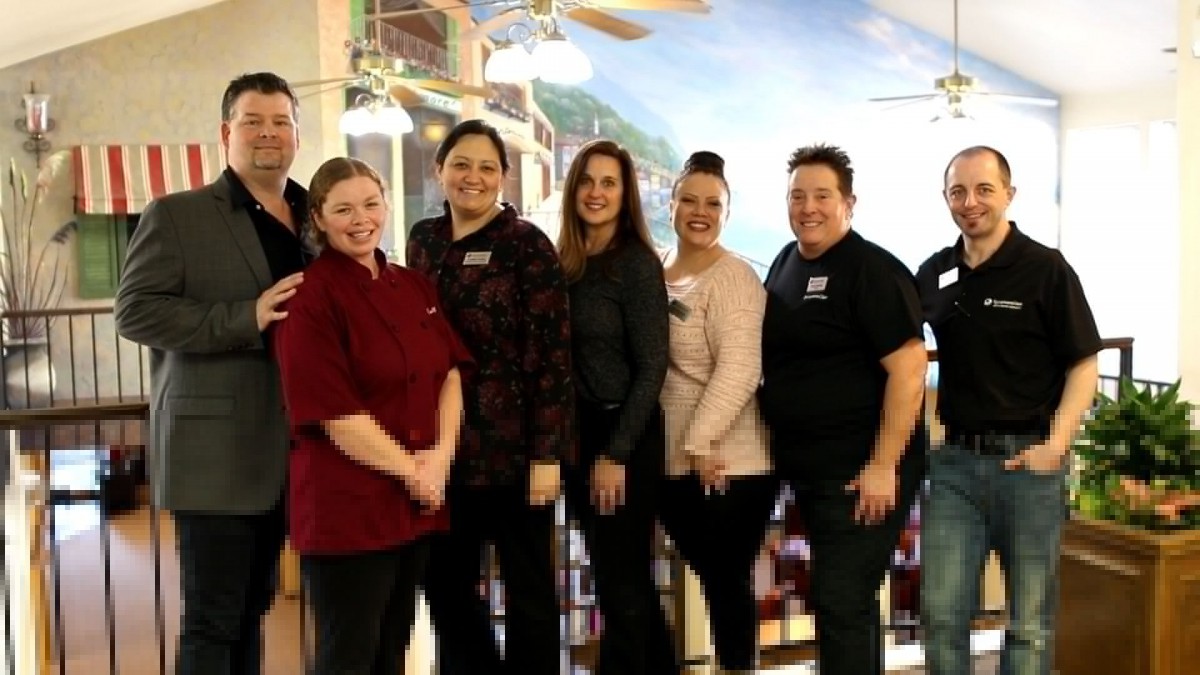 A group of people posing together indoors, smiling at the camera.