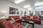 A modern living room featuring red leather sofas and contemporary artwork.