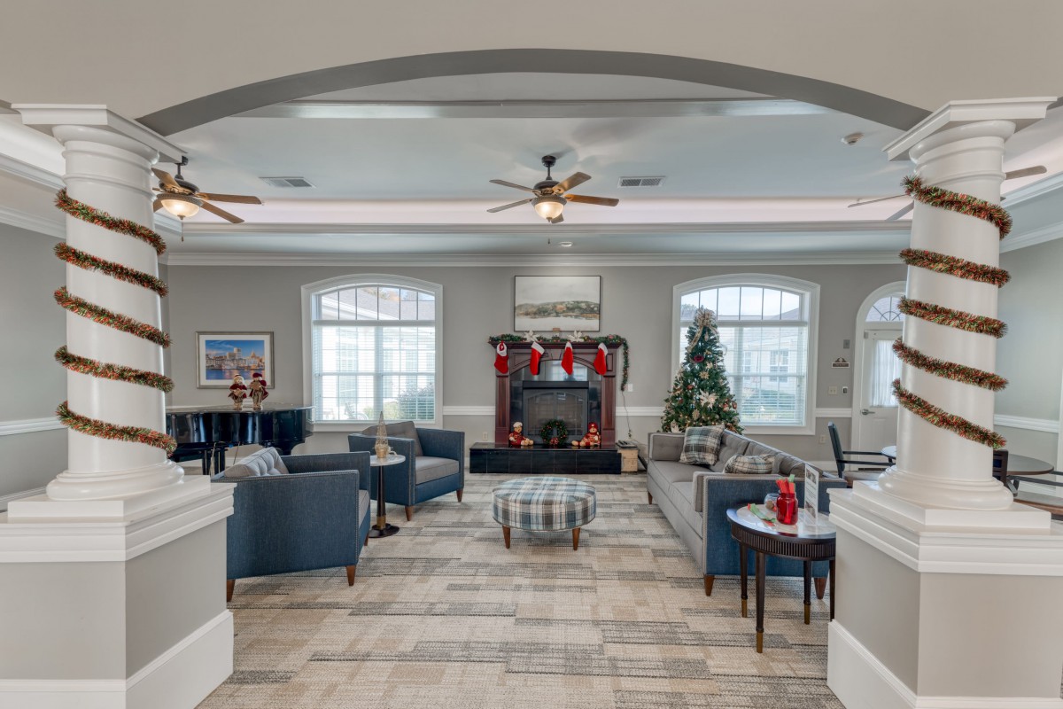 A cozy living room with Christmas decorations, featuring comfortable seating and a warm fireplace.