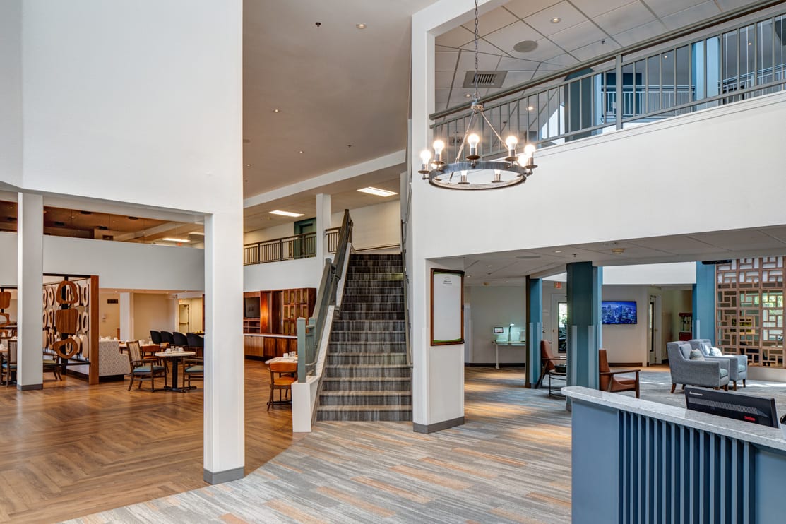 A modern lobby area featuring a staircase, chandelier, and comfortable seating.