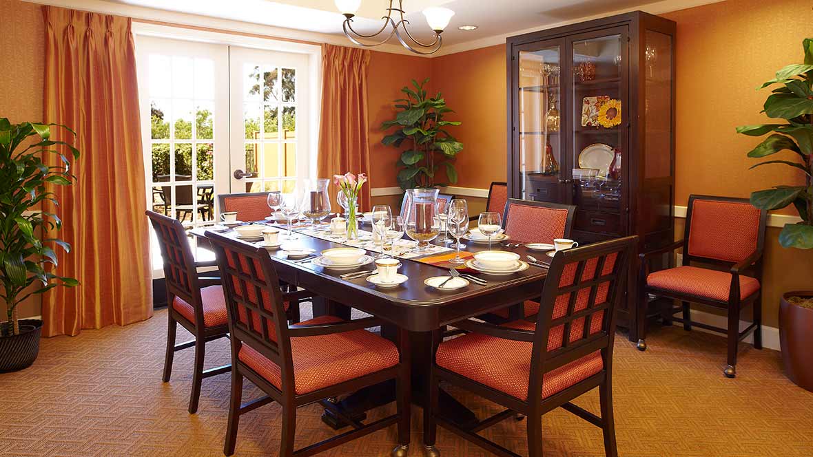 A well-decorated dining room featuring a large table set for a meal, with a chandelier overhead and a china cabinet in the background.