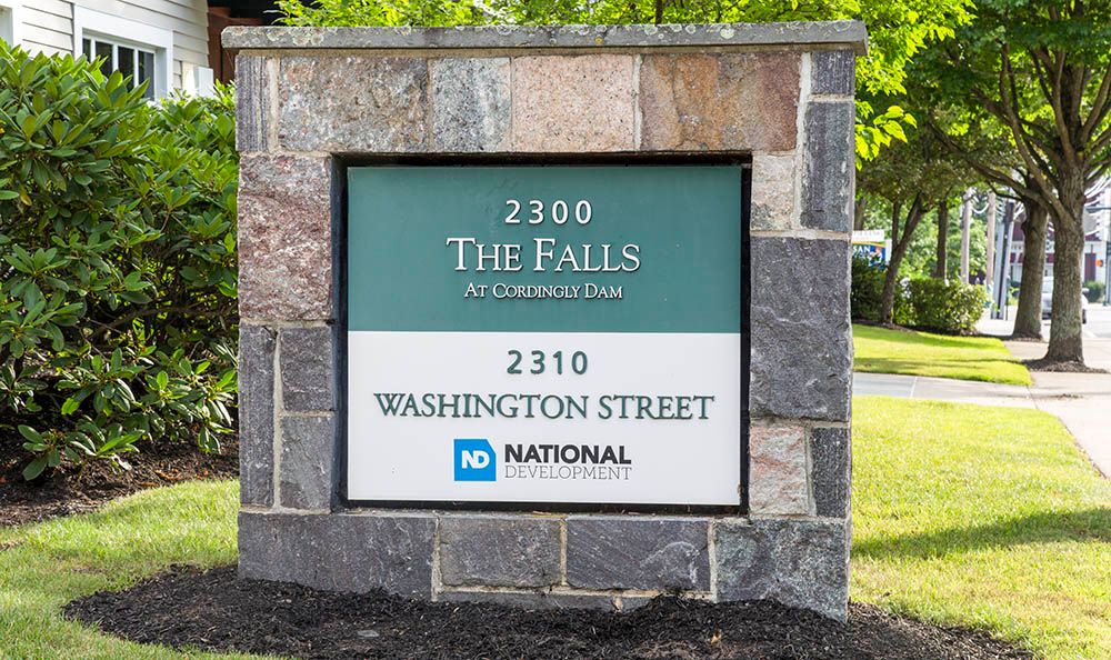 A stone sign displaying the address for 'The Falls' and 'National' on Washington Street.