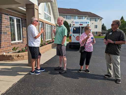 A group of four people engaged in conversation outside a building on a sunny day.