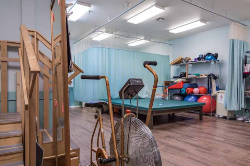 A physical therapy room equipped with exercise machines and rehabilitation tools.