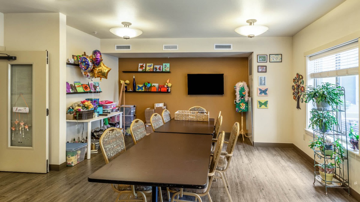 A well-lit meeting room with a long conference table, chairs, wall decorations, and colorful balloons.