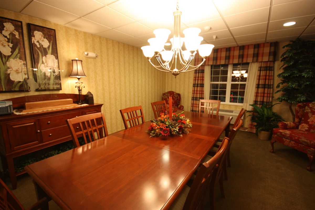 A warm and inviting dining room with a large wooden table, surrounded by chairs under a chandelier.