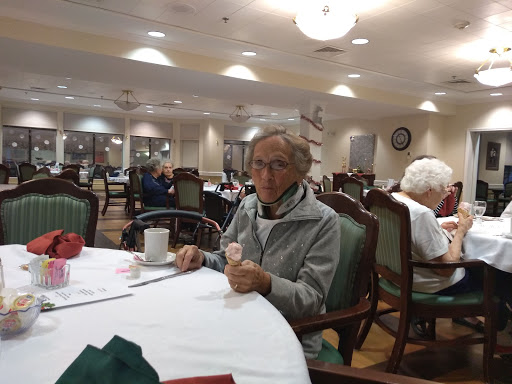 An elderly person enjoying a meal in a dining hall.