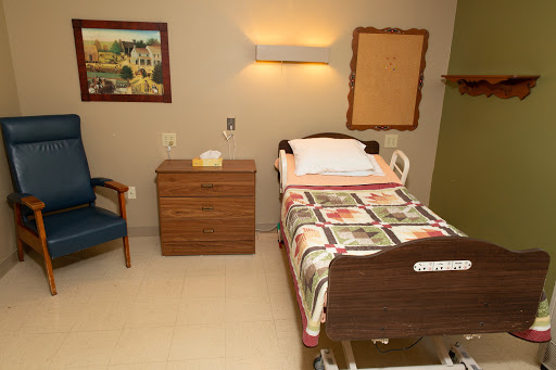 A well-furnished hospital room featuring a patient bed, nightstand, and cozy decor.