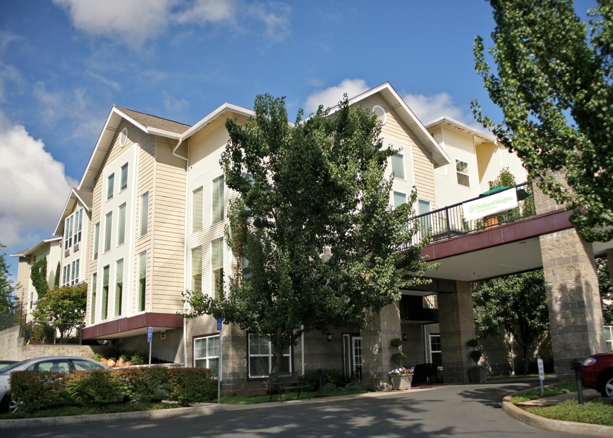 Exterior view of a hotel surrounded by trees on a sunny day.
