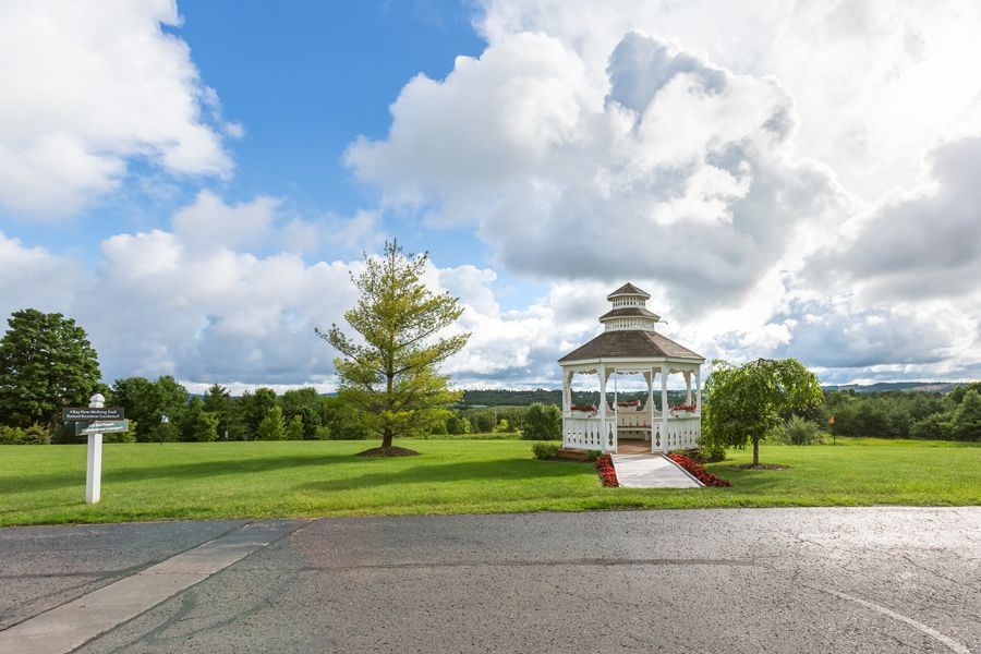 A picturesque gazebo set in a lush, green park under a partly cloudy sky.