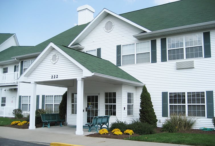 A suburban residential building with a green roof and white siding.