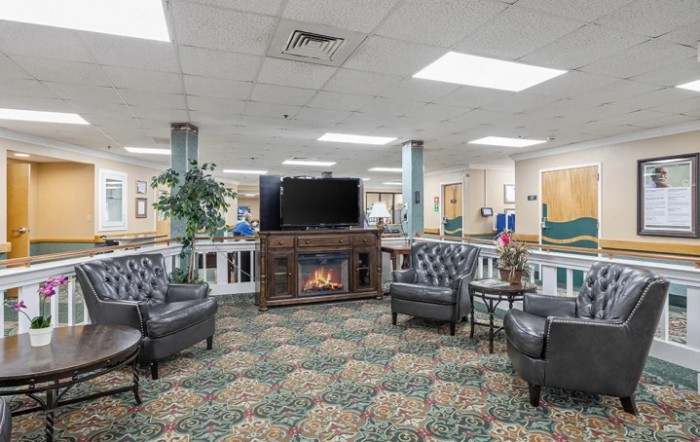 A cozy lobby with seating, fireplace, and television.