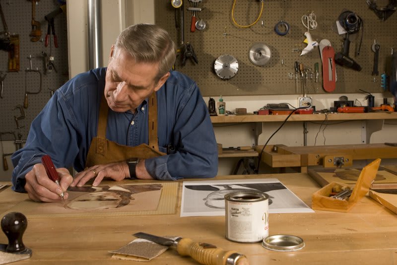 A craftsman working meticulously in his workshop, surrounded by tools and creating a detailed piece of art.