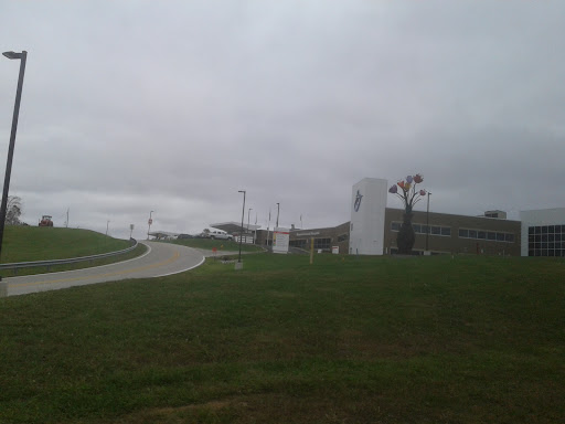 A view of a modern building under a cloudy sky, featuring signs and manicured grass.