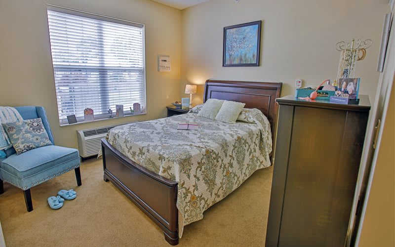 A cozy bedroom with a large bed, wooden furniture, and a window letting in natural light.
