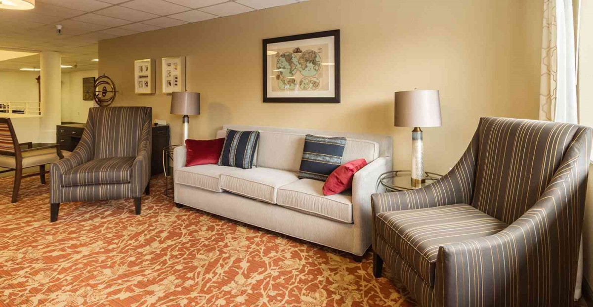A cozy living room with a neutral-toned sofa, accented cushions, and stylish lamps, complemented by artwork on the wall.