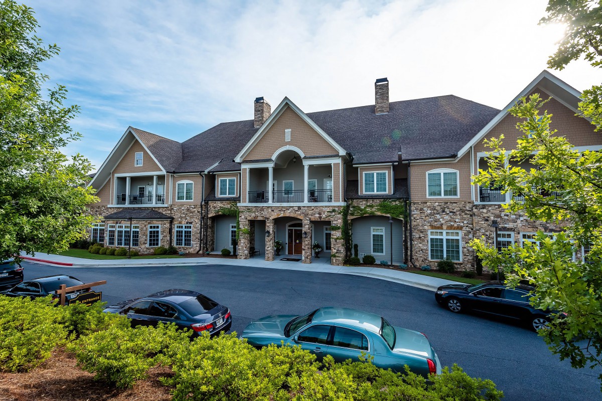 A large residential building with several cars parked in the driveway.