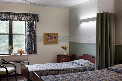 A cozy bedroom featuring two beds, a window with curtains, and decorative elements on the wall.