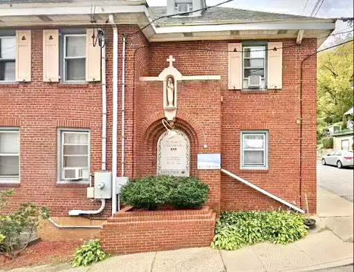 A brick church featuring a religious statue at its entrance.