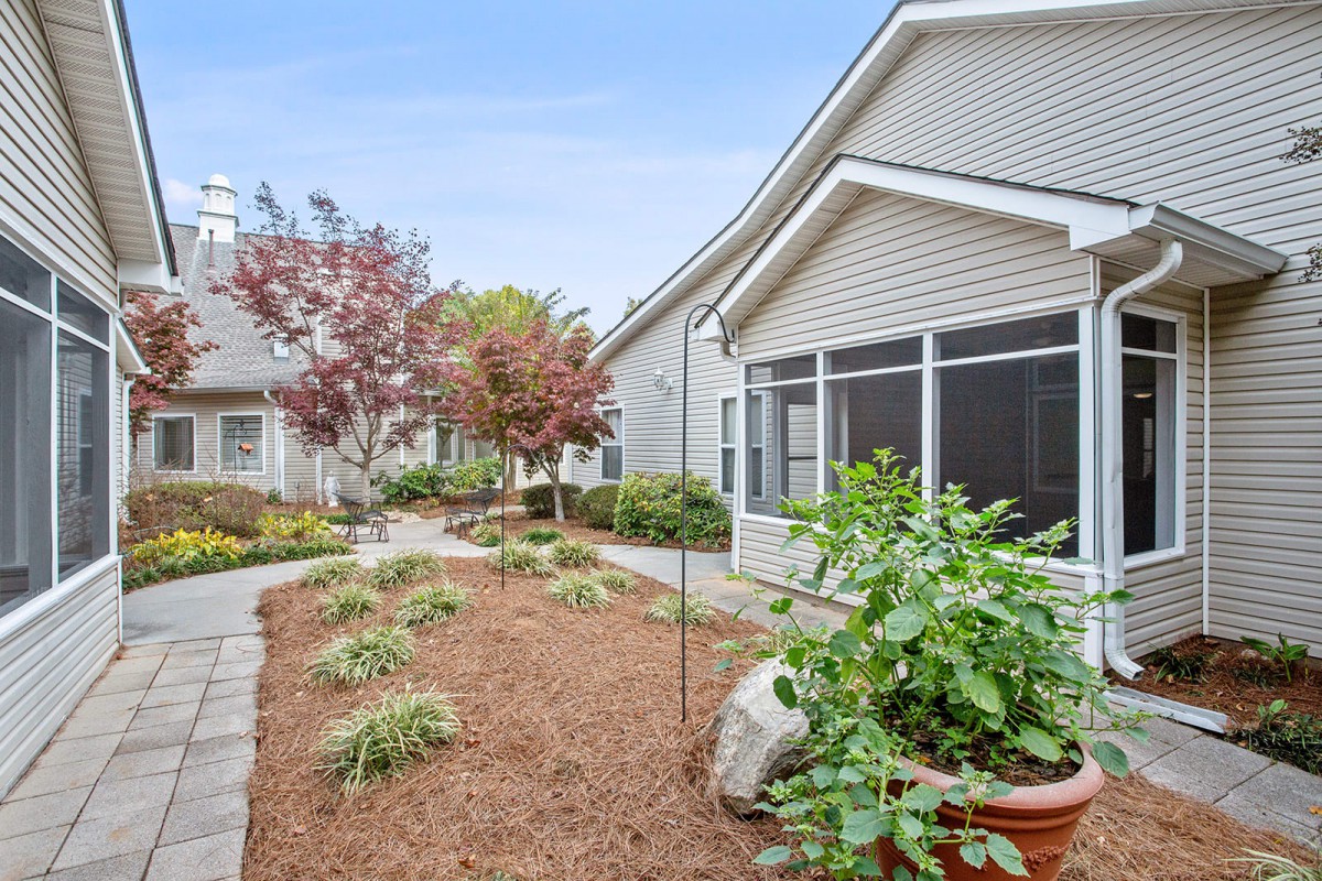 A well-maintained garden and pathway leading to a residential house with a screened porch.