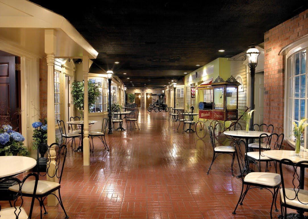 A quaint indoor hallway with tables and chairs, resembling a cafe setting.